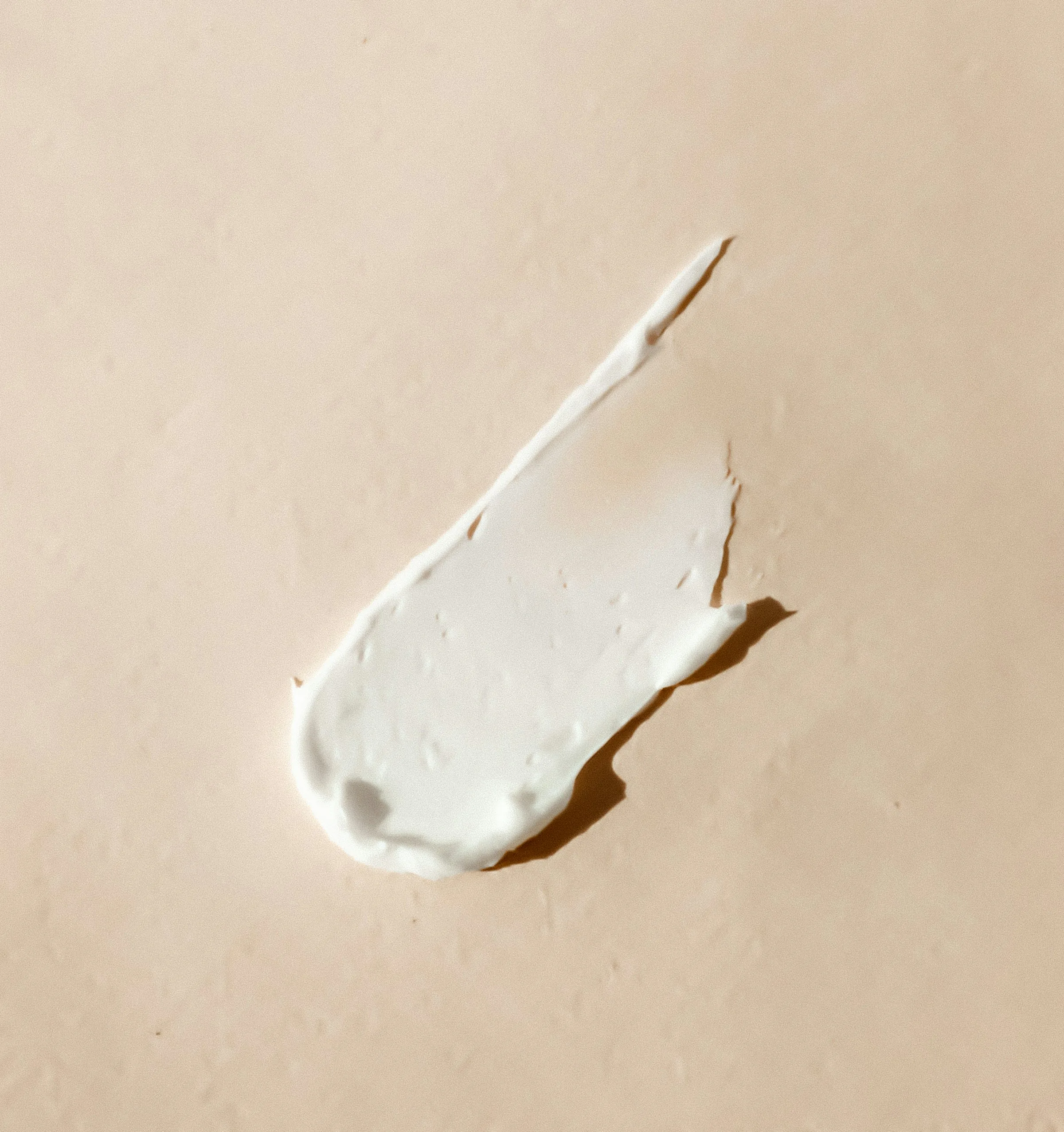 A swipe of white balm on a beige surface