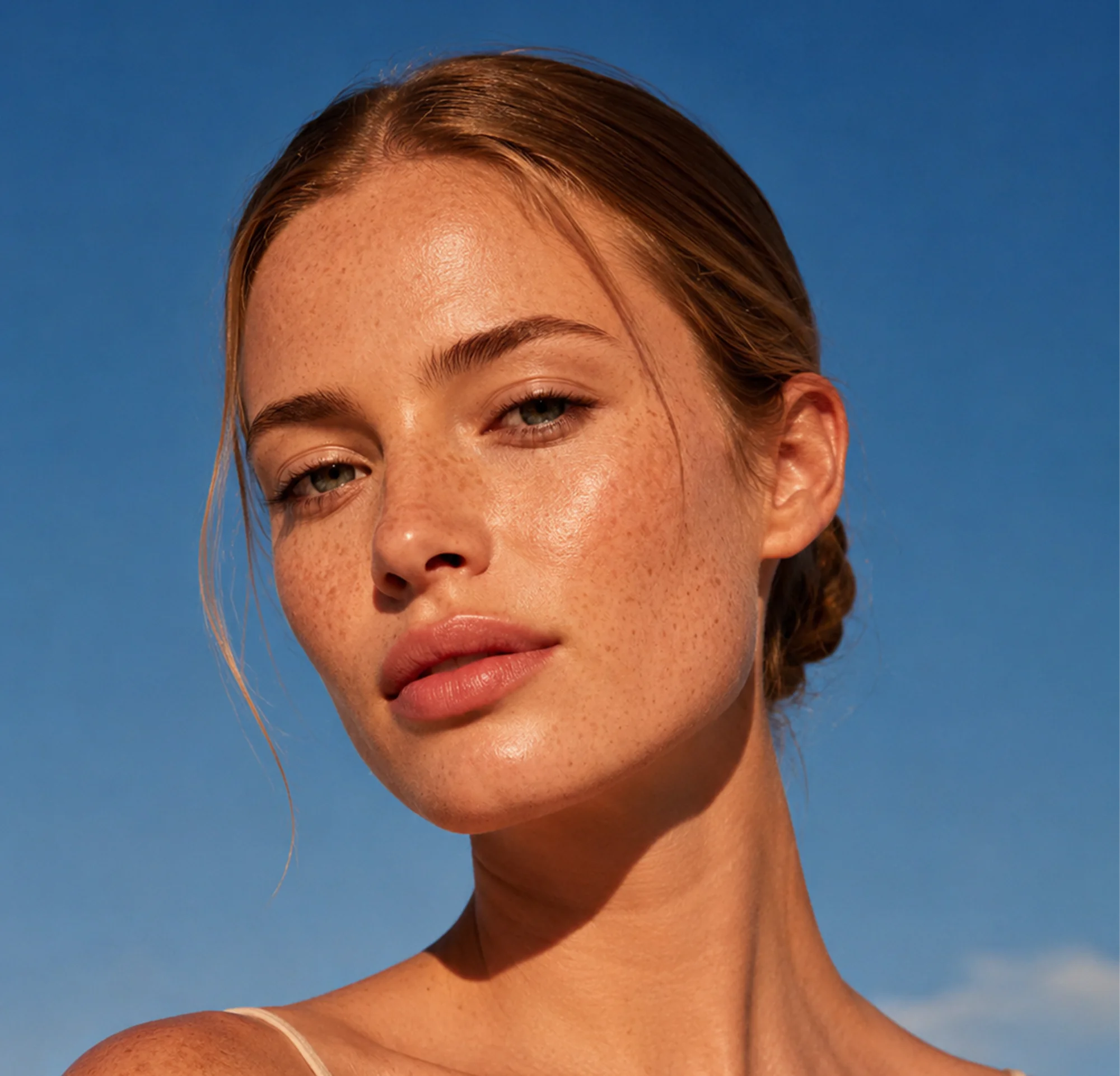 A freckled woman against a deep blue sky