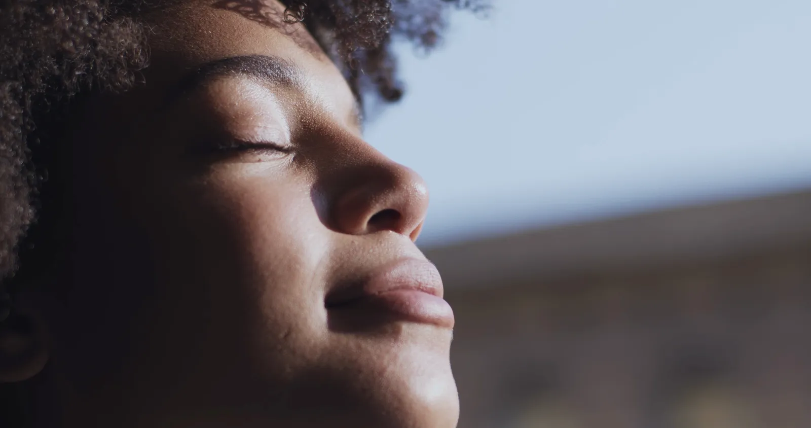 A woman with her eyes closed, face tipped up into the sun